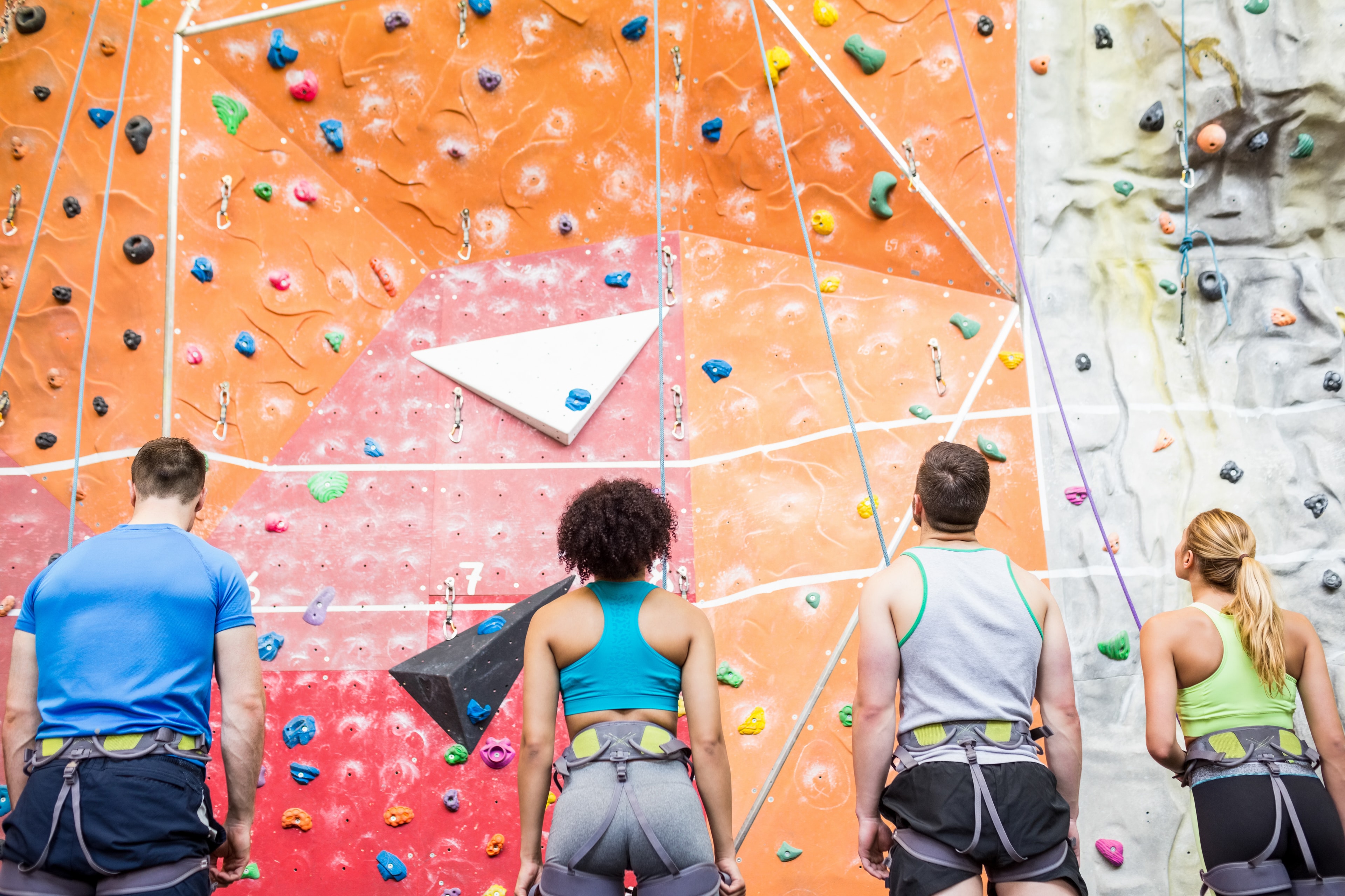 People climbing a colorful rock wall together, representing challenge and growth
